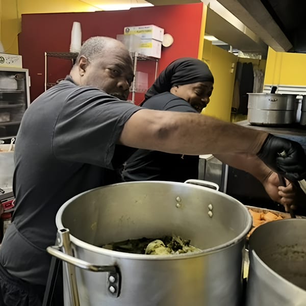 Two chefs, a man and a woman, prepare southern cuisine in a bustling kitchen.