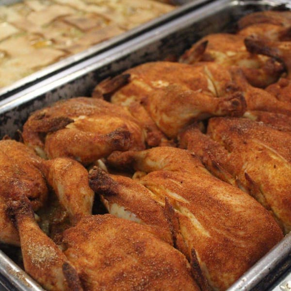 A tray of whole roasted chickens, seasoned with southern spices, ready to be served.