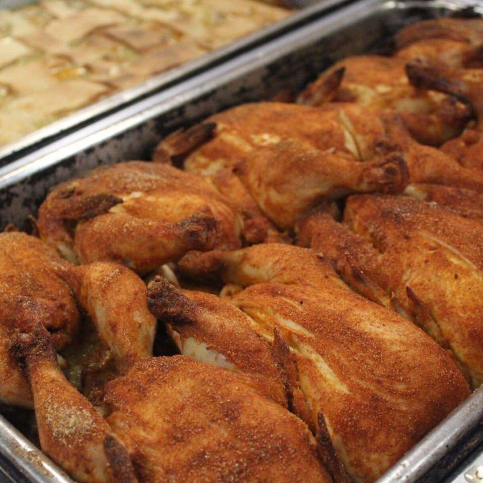 A tray of whole roasted chickens, seasoned with southern spices, ready to be served.