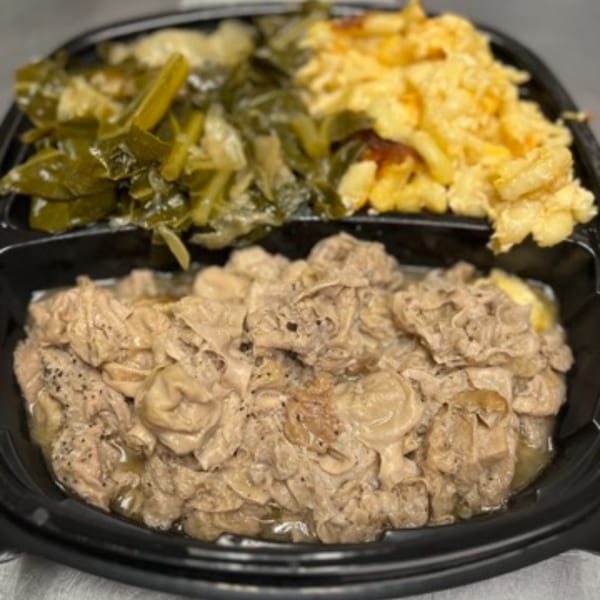 Chef Daddy's southern meal with chitterlings, collard greens, and macaroni and cheese in a black container.