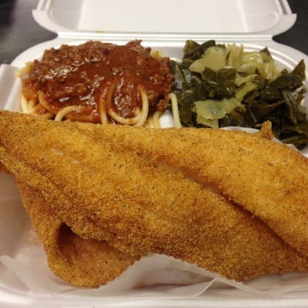 Chef Daddy's fried fish, spaghetti with meat sauce, and collard greens in a takeout container.
